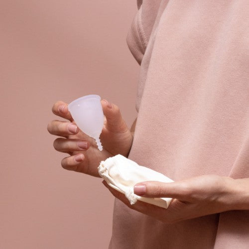 une femme range sa cup menstruelle dans son sachet