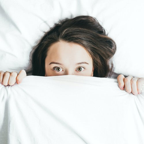 Une femme sort sa tête de sous la couette