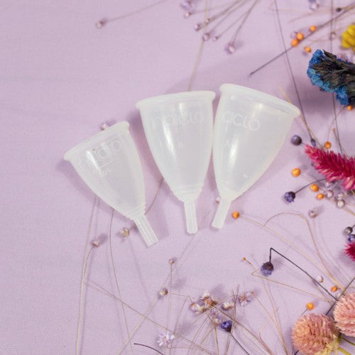 trois cups menstruelles sur un fond violet fleurit