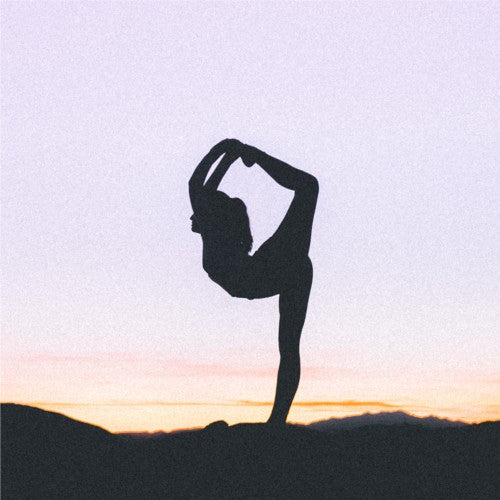 une femme tient une position de yoga au levé du soleil
